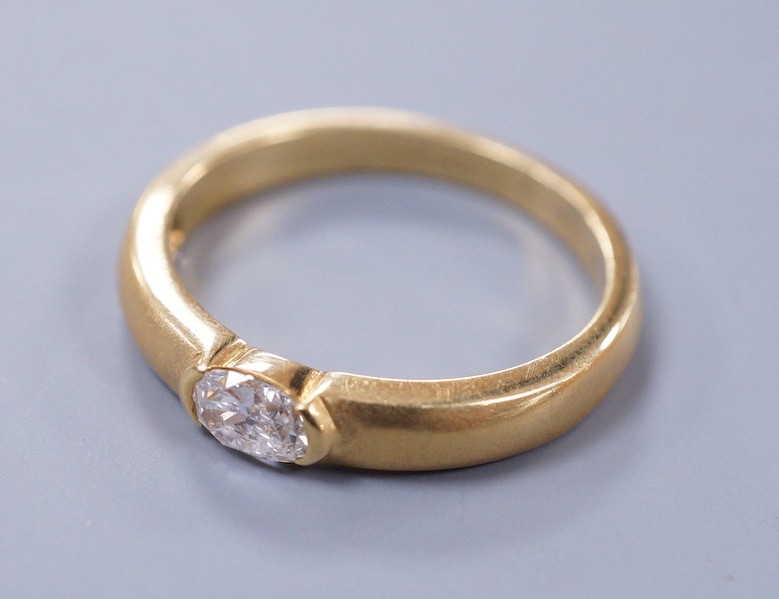 A modern 18ct gold and oval cut solitaire diamond set ring, with sandblasted shank, size K, gross weight 4 grams